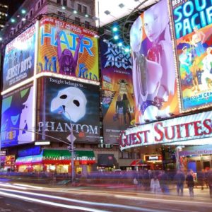 Image shows huge digital screens in Times Square, New York, displaying advertisements for musicals and shows