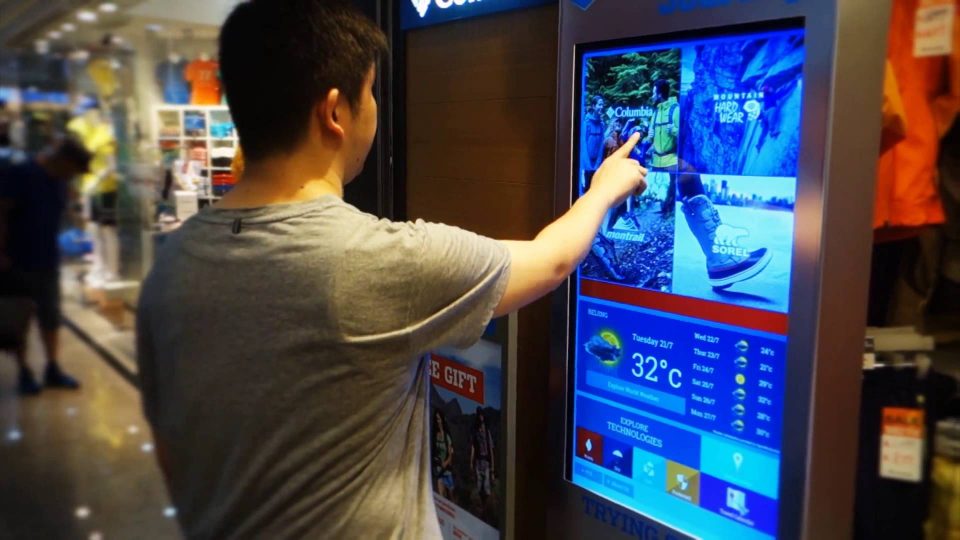 Image shows a young man using an interactive digital screen in a shop