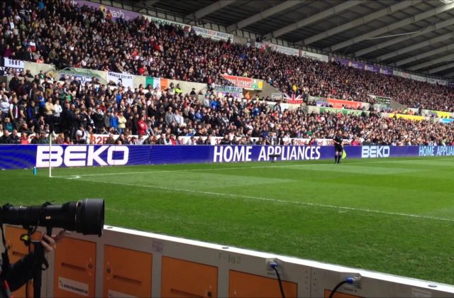 Image shows digital screen advertising surrounding football pitch