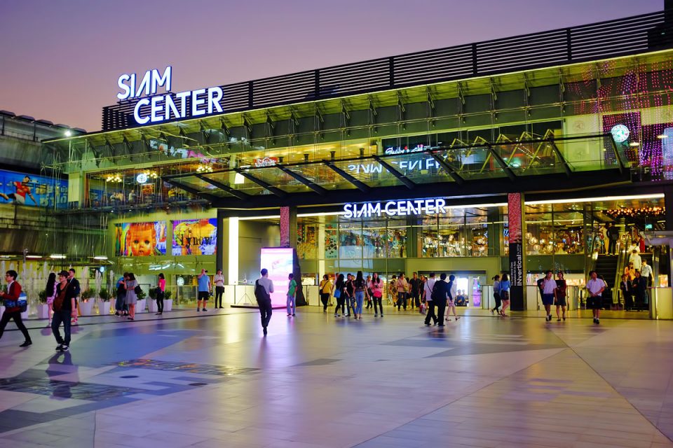 Image shows the exterior of a large shopping centre lit up with digital screens