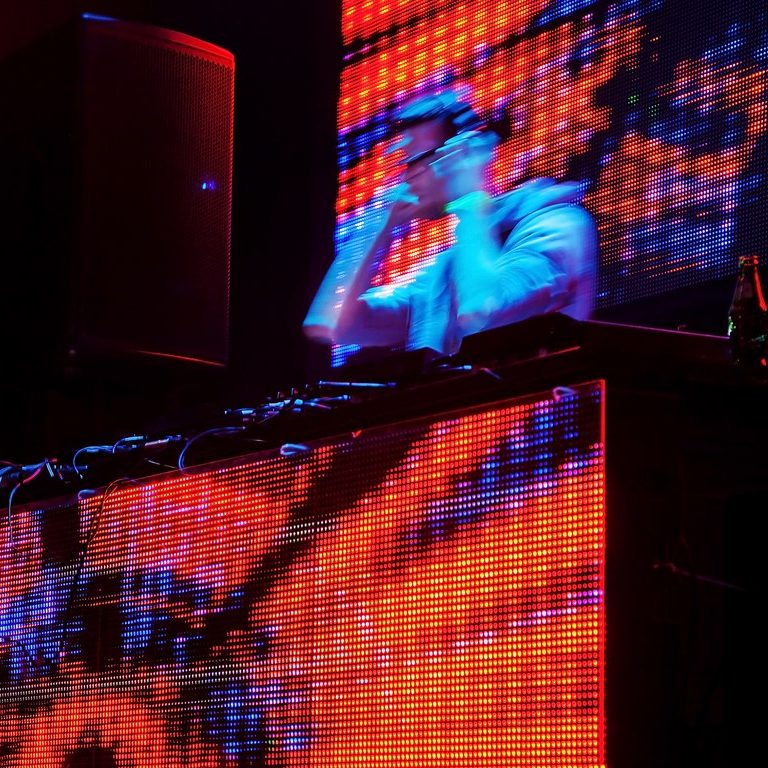 Image shows large screens on and above a DJ booth