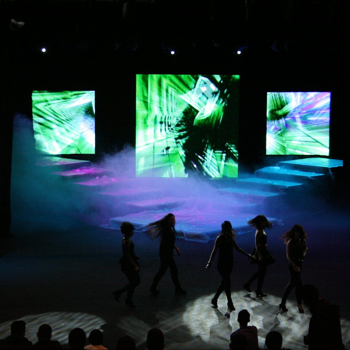 Image shows large screens illuminating a stage for a production